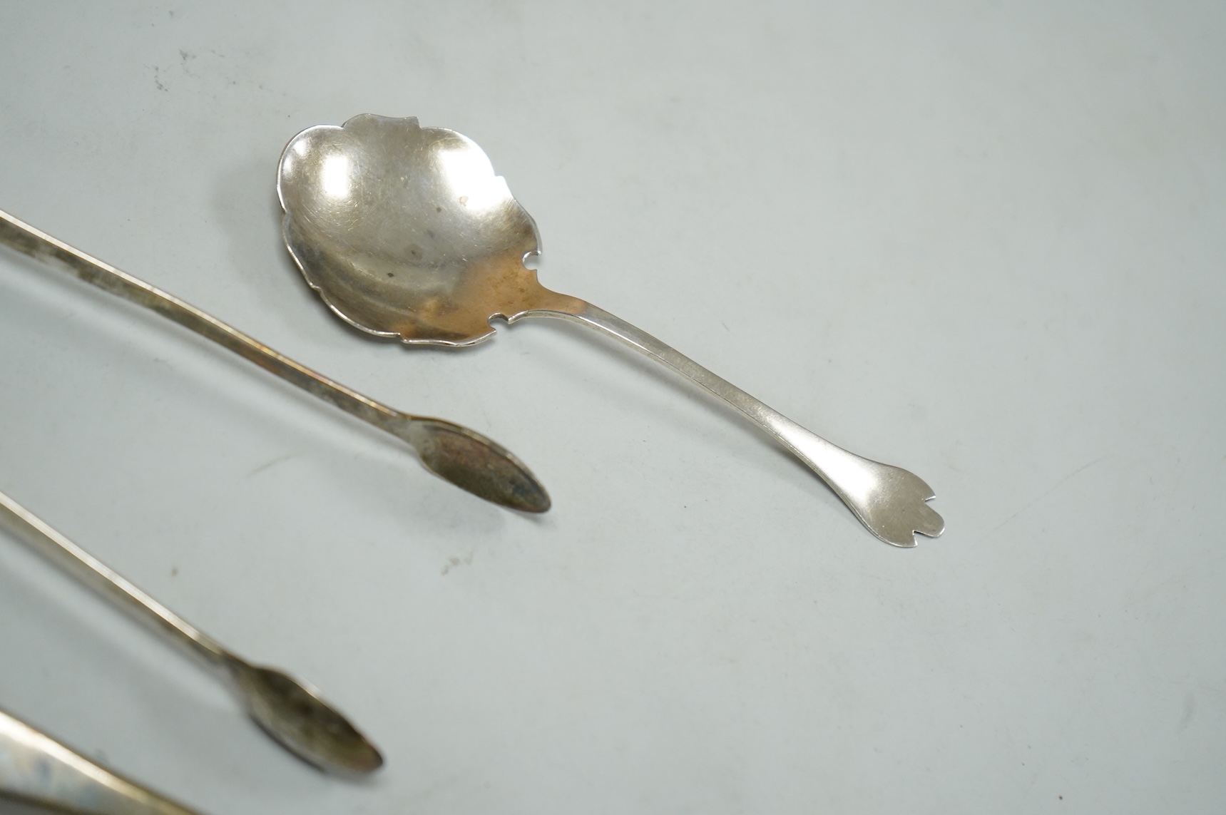 A pair of George V silver grape shears, Josiah Williams & Co, London, 1912, 16.2cm, together with a George III silver Old English pattern sifter spoon, Eley & Fearn, London, 1801, a similar pair of sugar tongs, London, 1